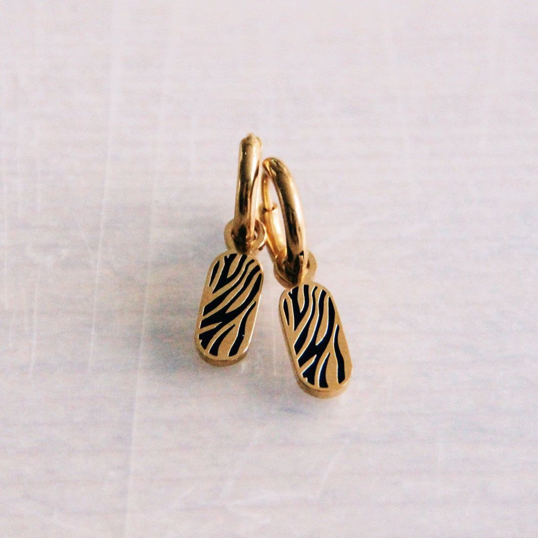 Edelstalen oorringen met tag met zebraprint – goud